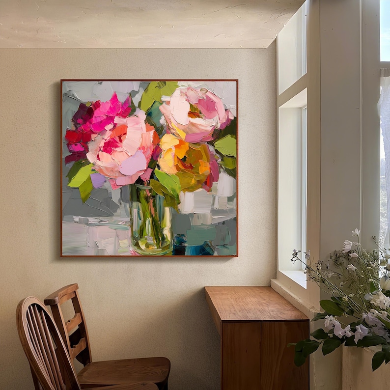 May include: Square framed floral painting featuring a bouquet of pink, red, and yellow flowers in a clear glass vase. The artwork has a textured, impressionistic style with visible brushstrokes and green leaves. The background is a mix of gray and white.