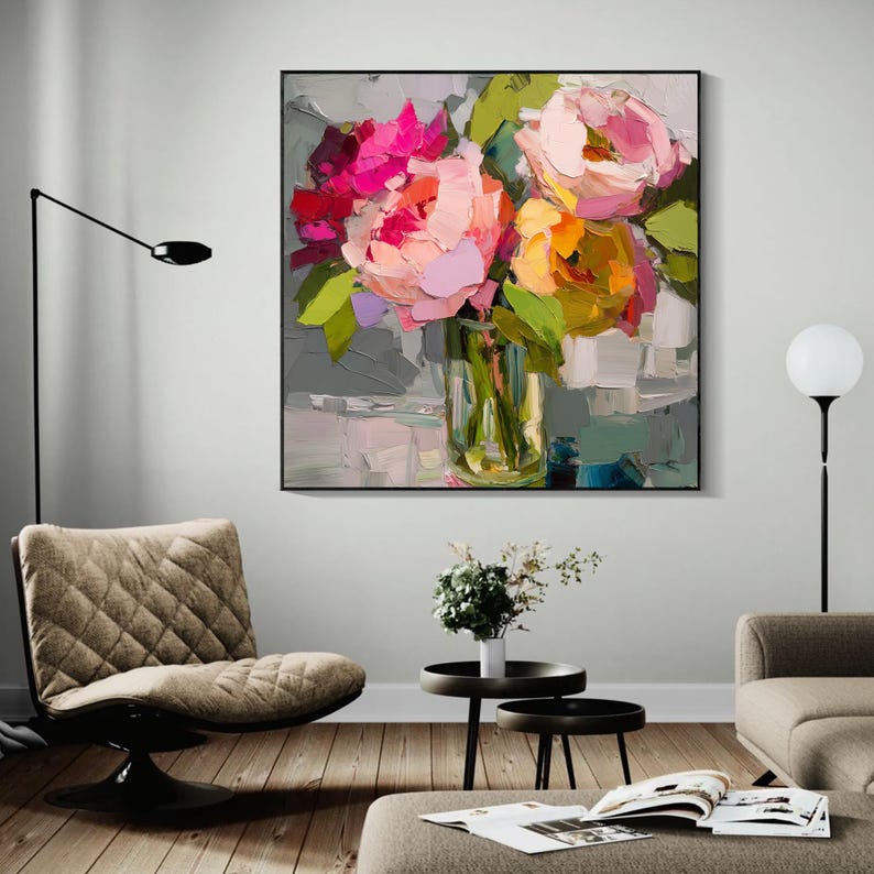 May include: A framed floral painting featuring a bouquet of colorful flowers in a glass vase. The flowers are painted with thick brushstrokes in shades of pink, orange, and yellow, with green leaves. The artwork is displayed in a modern living room setting.