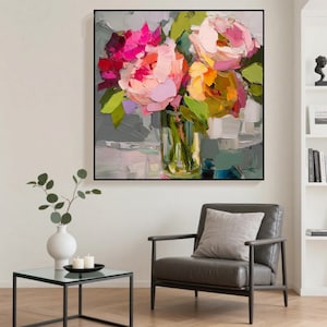 May include: An abstract painting of a floral arrangement in a clear glass vase. The flowers are a mix of pink, peach, and yellow, with green leaves. The painting is in a black frame and hangs on a gray wall.