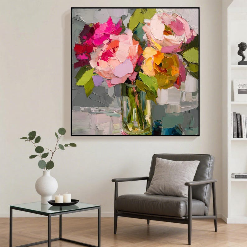 May include: An abstract painting of a floral arrangement in a clear glass vase. The flowers are a mix of pink, peach, and yellow, with green leaves. The painting is in a black frame and hangs on a gray wall.