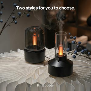 May include: Two aroma diffusers with black bases and clear glass covers, one cylindrical and one rounded, emitting mist and orange light. The text "Two styles for you to choose." and "Kinscoter" are visible. Both devices have power buttons.