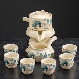 Può includere: Un servizio da tè color crema con un design paesaggistico nei toni del blu e del verde. Il set comprende una teiera con coperchio, una brocca e sei piccole tazze. Il servizio da tè è in ceramica.