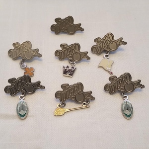 Set of collectible Wicked Wizard of Oz lapel pins with broom, cross, scroll, crown, heart and Emerald City charms