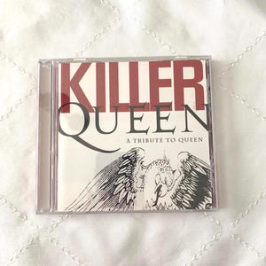 May include: A clear plastic CD jewel case containing the album Killer Queen: A Tribute to Queen. The cover features the text Killer Queen in large red and black letters, with the subtitle A Tribute to Queen and a black and white bird illustration.
