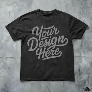 May include: A black t-shirt with the text "Your Design Here" in a stylized, light gray font. The shirt has a crew neck and short sleeves. The fabric has a slightly faded, vintage appearance.