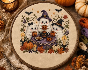 May include: A circular embroidery hoop containing a cross-stitch pattern of three white ghosts wearing hats, sitting at a purple table with jack-o'-lantern mugs, a teapot, and cookies, surrounded by autumn leaves, candles, and small bats.