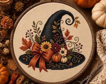 Può includere: Un ricamo a punto croce in un telaio circolare in legno raffigurante un cappello da strega blu scuro decorato con un fiocco arancione, un girasole giallo, zucche, bacche rosse e foglie autunnali su tessuto color crema.