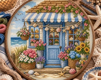 Può includere: Un ricamo circolare a punto croce che raffigura una casa sulla costa con una tenda a righe blu, una porta blu centrale e finestre. La scena è decorata con vari fiori in vaso, cesti appesi e una ghirlanda di conchiglie e stelle marine.