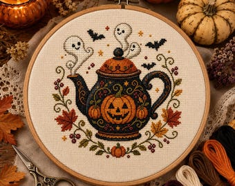 Può includere: Un telaio da ricamo circolare in legno contenente un motivo a punto croce di una teiera scura decorata con una faccia di zucca, circondata da piccoli fantasmi bianchi, pipistrelli neri, foglie autunnali e bacche su tessuto color crema.