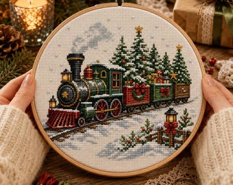 Può includere: Un telaio da ricamo circolare in legno contenente un motivo a punto croce di una locomotiva a vapore nera e verde che traina vagoni carichi di alberi di Natale decorati e regali, su un paesaggio innevato con una staccionata e una lanterna.