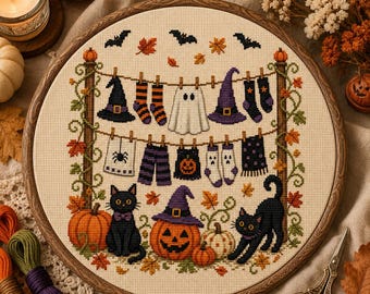Può includere: Un telaio da ricamo circolare in legno contenente un disegno a punto croce di oggetti di Halloween appesi a un filo, tra cui cappelli da strega, calzini, un fantasma e un asciugamano, con gatti neri e zucche sul fondo.