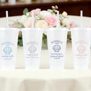 May include: Four clear plastic cups with lids and straws, each with a seashell design and the words "Seashells and Wedding Bells." The cups have different text, including names and dates, in blue and tan.