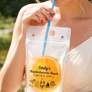 以下が含まれることがあります： 青いストローが付いた透明なプラスチック製のドリンクポーチ。黒い文字で「Emily's Bachelorette Bash March 9, 2026」と印刷され、カクテル、貝殻、ビキニ、ヨット、ミラーボールのアイコンが描かれており、中にはオレンジのスライスが入っています。