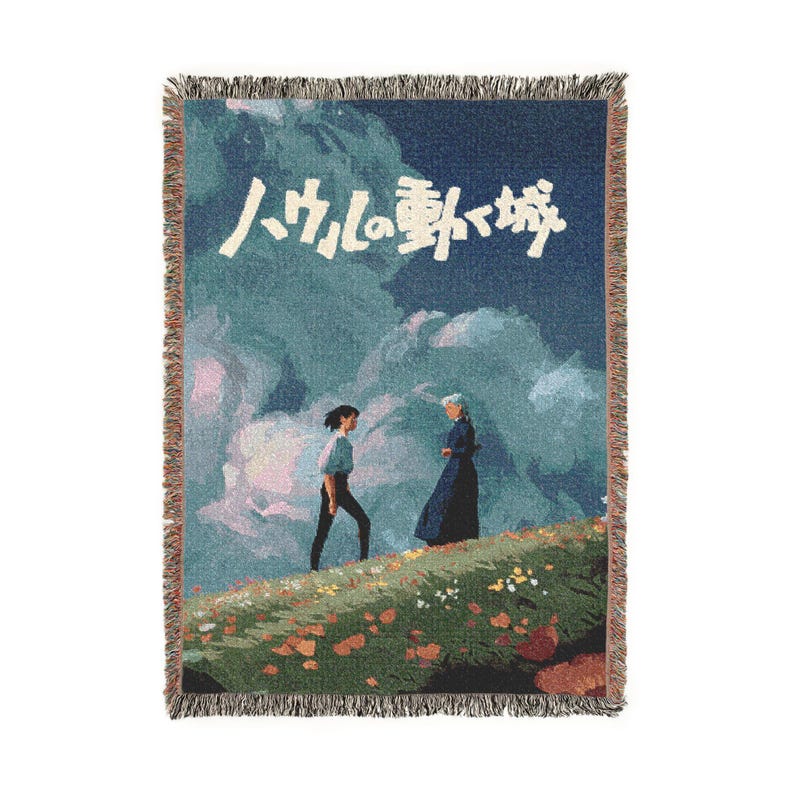 Pode incluir: Uma manta tecida com uma cena de um filme de anima&ccedil;&atilde;o japon&ecirc;s. O design mostra duas figuras numa colina gramada com um fundo de c&eacute;u nublado. O texto japon&ecirc;s est&aacute; no topo. A manta tem uma borda com franjas.