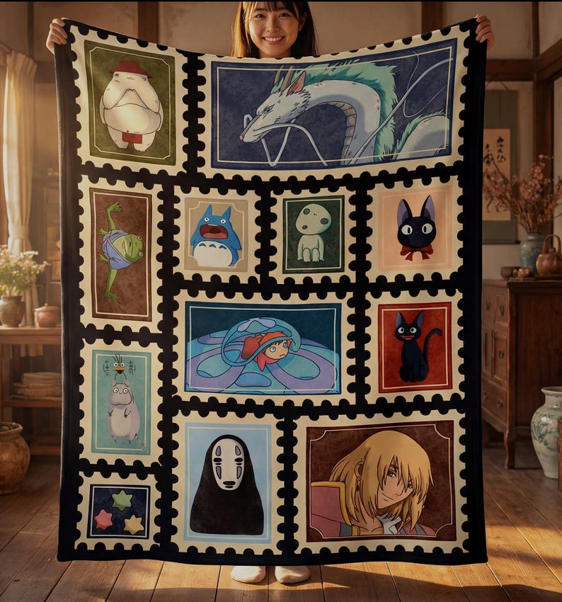 May include: A large, rectangular blanket featuring a patchwork design of various anime characters in postage stamp-like frames. The blanket has a black border and a cream-colored background. The characters include a dragon, a cat, and other animated figures.