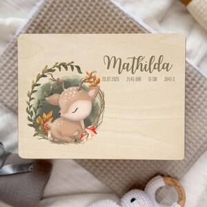 以下が含まれることがあります： 木製のプレートに「Mathilda」という名前がエレガントな筆記体で書かれています。 葉に囲まれた子鹿の水彩イラストが特徴です。 プレートには、20.07.2025、21:45、51cm、3845gの誕生日の詳細が含まれています。