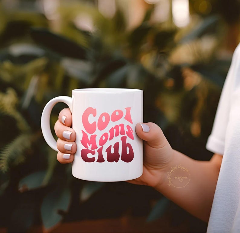 May include: A white ceramic mug with a black handle and the text "But First, Coffee" in a black, handwritten-style font. The mug is on a white surface.