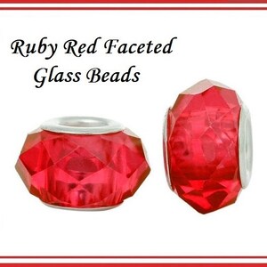 May include: Two faceted ruby red glass beads with silver-coloured accents. The beads have a geometric design and are displayed against a white background. Text in the image reads "Ruby Red Faceted Glass Beads."