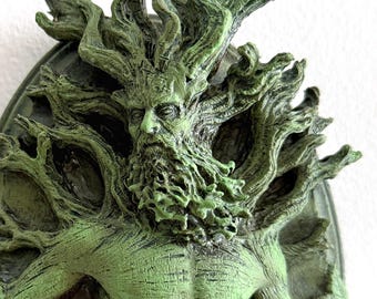 Könnte beinhalten: Eine grüne, geformte Wanddekoration eines Mannes mit einem Baum, der aus seinem Kopf und Körper wächst. Der Mann hat einen Bart und ist von Blättern und Blumen umgeben.