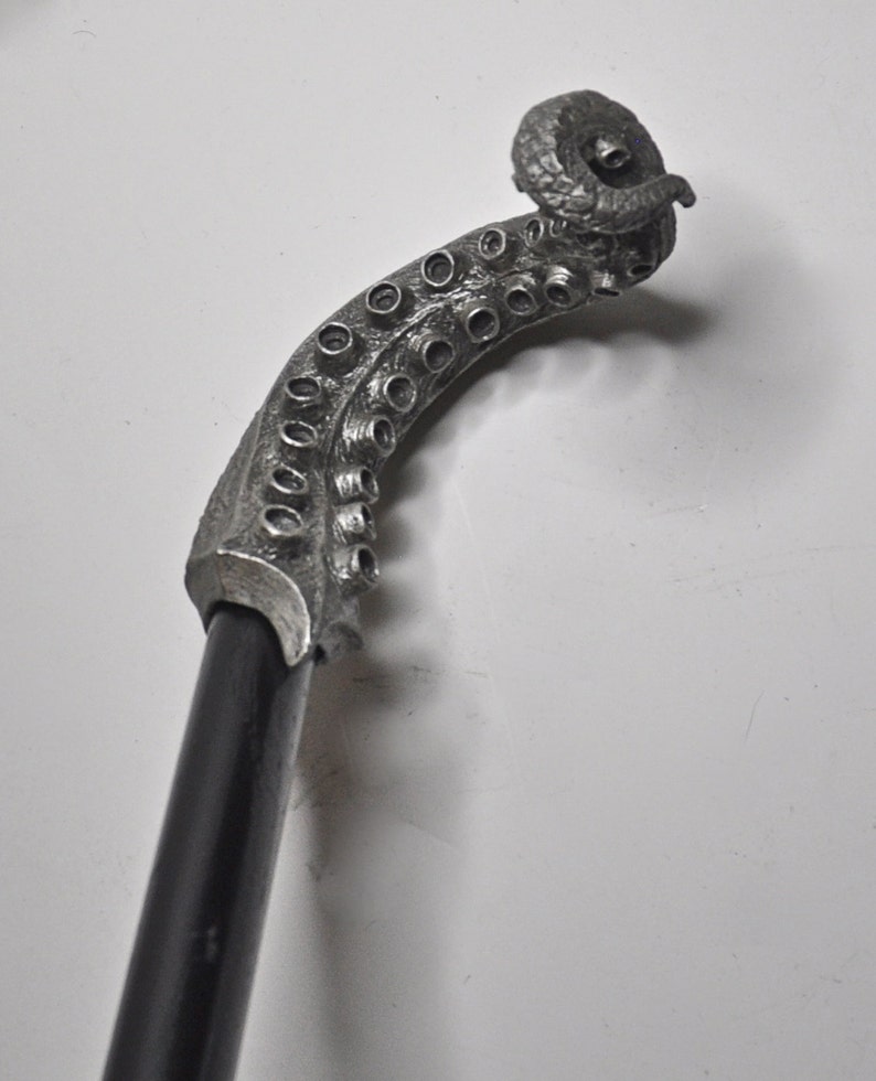 May include: A silver walking stick with an octopus-shaped handle. The handle is curled and has a textured surface.