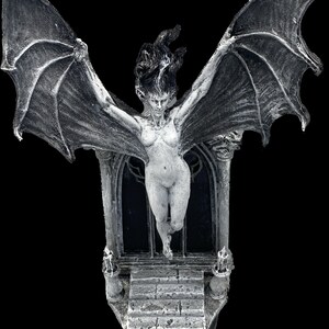 Pode incluir: Uma figura feminina branca alada com cabelo comprido, de p&eacute; em uma porta de pedra com um arco g&oacute;tico. A figura &eacute; esculpida em uma pose dram&aacute;tica com as asas estendidas.