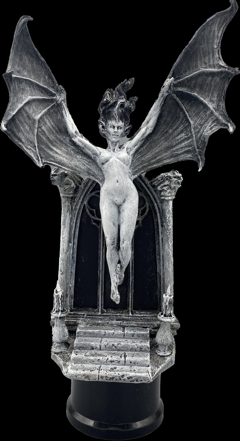 Pode incluir: Uma est&aacute;tua de uma figura feminina alada branca com um arco g&oacute;tico e degraus. A est&aacute;tua &eacute; feita de resina e tem um acabamento detalhado e texturizado.