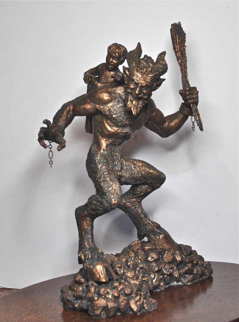 May include: A bronze sculpture of a satyr carrying a small child on his back. The satyr is holding a stick in his right hand and a chain in his left hand. The sculpture is set on a base of rocks.