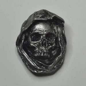 May include: A silver-colored pewter skull pendant with a hooded cloak design.
