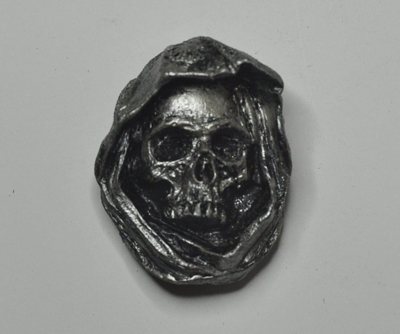 May include: A silver-colored pewter skull pendant with a hooded cloak design.