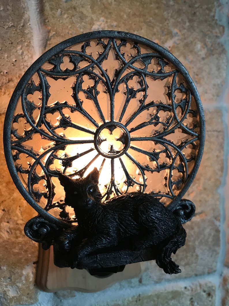 Peut inclure: Une veilleuse en forme de chat noir avec un motif de vitrail. Le chat est assis sur un rebord avec une ampoule &agrave; l'int&eacute;rieur du cercle de vitrail.
