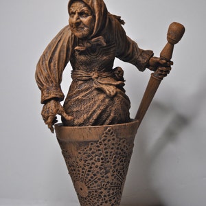 May include: A brown ceramic sculpture of a woman holding a wooden pestle. The woman is wearing a brown dress and a brown head covering. The sculpture is standing in a brown ceramic mortar.