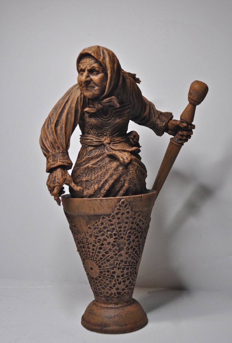 May include: A brown ceramic sculpture of a woman holding a wooden pestle. The woman is wearing a brown dress and a brown head covering. The sculpture is standing in a brown ceramic mortar.