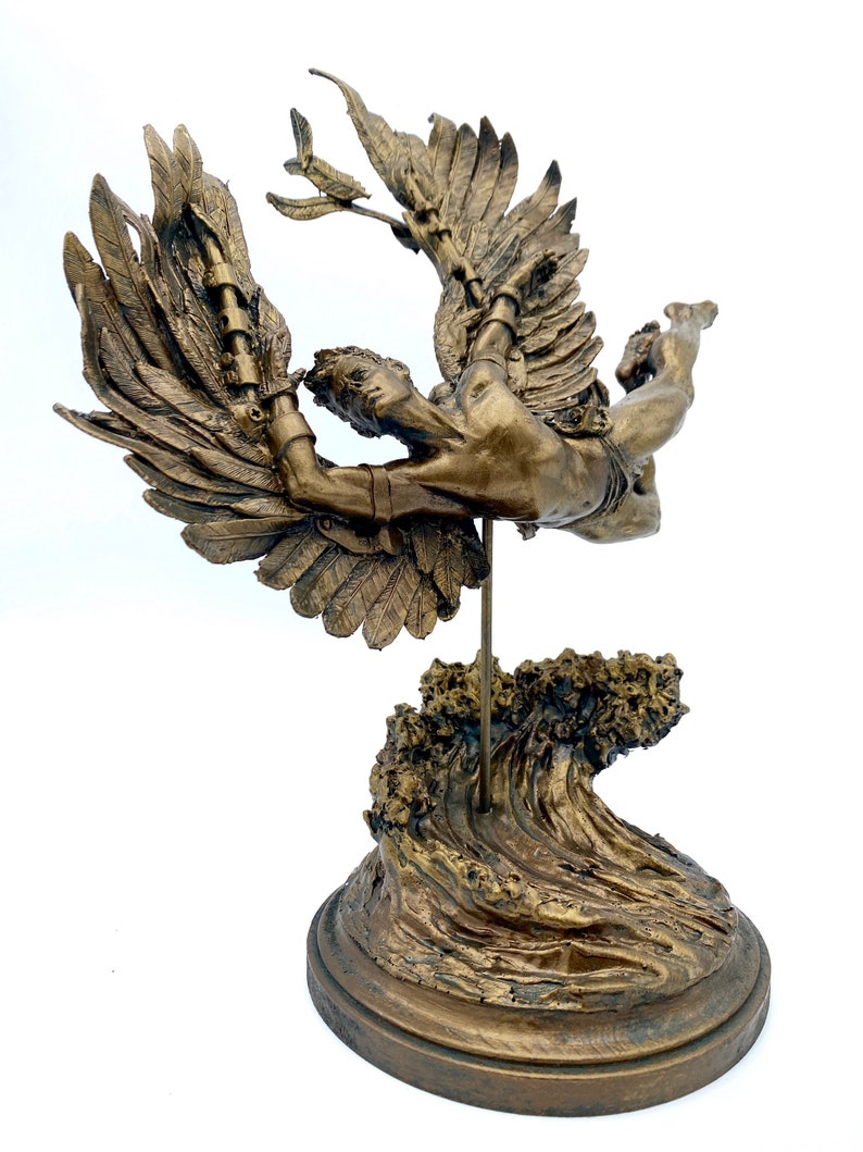 May include: A bronze sculpture of a winged figure with outstretched arms, soaring above a wave base. The figure is depicted in mid-flight, with its wings spread wide and its body tilted forward. The sculpture is mounted on a circular base, which is decorated with a wave design.