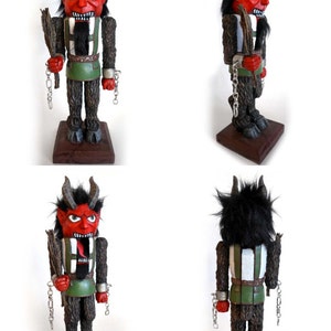 May include: A red and black wooden nutcracker with horns, a beard, and chains. The nutcracker is holding a stick in its right hand. The nutcracker is standing on a wooden base.