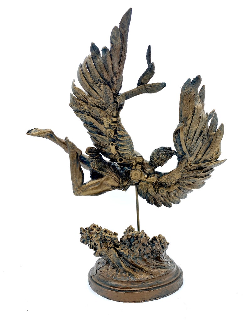 May include: A bronze sculpture of an angel with wings outstretched, falling into a wave. The angel is depicted with a human body and feathered wings. The sculpture is mounted on a base that resembles a wave.
