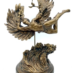 May include: A bronze sculpture of a winged figure with outstretched arms, standing on a wave-shaped base. The figure is depicted in mid-flight, with wings spread wide and a determined expression on its face.