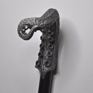 May include: A silver-colored walking stick with a detailed, sculpted octopus head handle. The handle has a textured surface and multiple round holes.