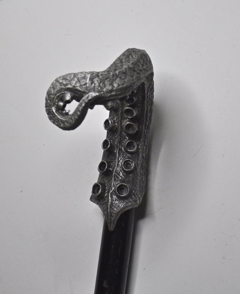 May include: A silver-colored walking stick with a detailed, sculpted octopus head handle. The handle has a textured surface and multiple round holes.