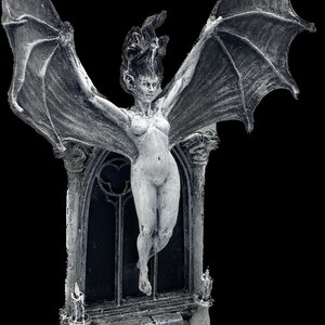 Pode incluir: Uma escultura de pedra cinzenta de uma mulher alada com cabelo comprido, de p&eacute; numa porta com uma janela de vitral. A escultura &eacute; detalhada com asas texturizadas e uma base de pedra.