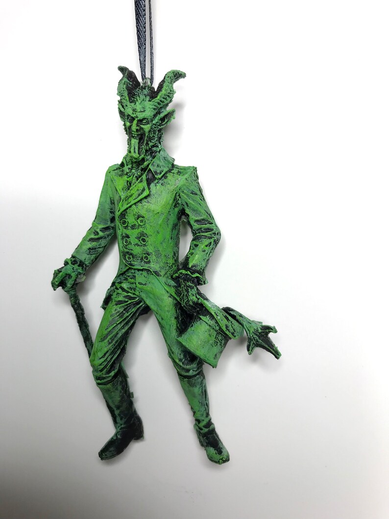 May include: Green, devil-like ornament with horns, a top hat, and a cane. The ornament is made of plastic and has a distressed paint finish.