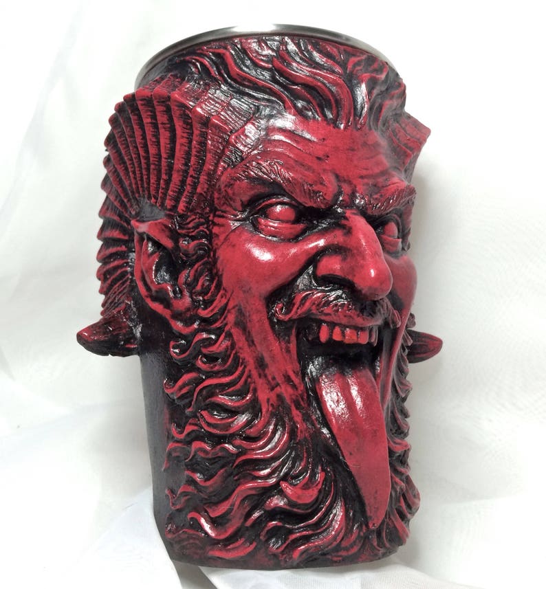 May include: Red ceramic mug shaped like a demon's head with a long tongue sticking out. The mug has a stainless steel rim.
