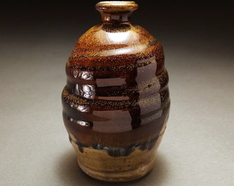 Shiny two toned brown and green wood fired bottle with yellow specks and streaks