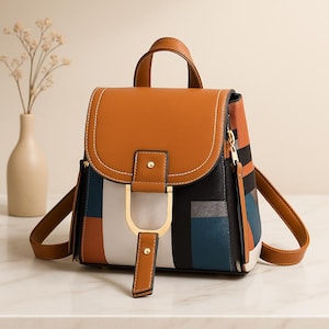 Peut inclure: Un sac à dos élégant avec un rabat et une poignée marron, orné d'un motif géométrique noir, blanc, bleu et orange. Le sac est doté d'une quincaillerie dorée et de bretelles réglables. Le design est moderne et chic.
