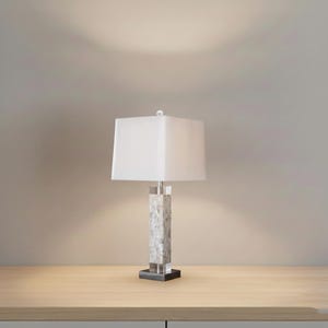 Lampada da tavolo moderna: base in pietra con texture a conchiglia, paralume in tessuto bianco.