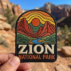 May include: An embroidered patch with an arched top featuring a landscape of red rock mountains, a blue river, green vegetation, and a yellow and orange sun. The text ZION NATIONAL PARK is embroidered in white and orange on a black background.