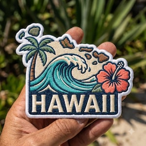May include: An embroidered patch featuring a beige background with a green palm tree, a large teal ocean wave, and a coral hibiscus flower. The patch displays the word HAWAII in bold beige letters against a dark blue rectangular base.