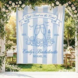 May include: A light blue and white striped banner with the text "Last Toast on the Coast" and "Emily's Bachelorette MIAMI, FL". The banner features illustrations of champagne glasses, seashells, and a lighthouse.