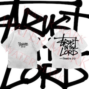 May include: A light gray short-sleeve t-shirt featuring black text on the front that reads Proverbs 3:5. The back of the shirt displays the black text Trust in the Lord with Proverbs 3:5 underneath in a bold, stylized graffiti-inspired font.