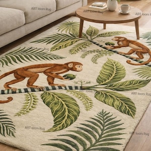 May include: Cream-coloured area rug with a jungle design. It features brown monkeys and green palm leaves. The rug has a soft, textured appearance and is placed in a living room setting. The words "ART loom Rug" are printed on the rug.
