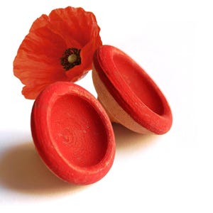May include: Two small, red, wooden bowls with a poppy flower on a white background. The bowls are painted a vibrant red, with a natural wood color visible on the sides. The poppy is a bright red with a dark center.